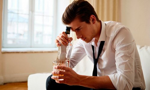 Мужчина сидит с алкоголем в руке